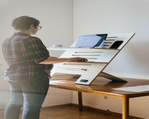Person adjusting the height of a laptop stand on a desk